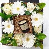 Mother's Day flowers and candle gift box featuring daisies, greenery, gerberas, white roses and a Birch + Bay Apothecary candle