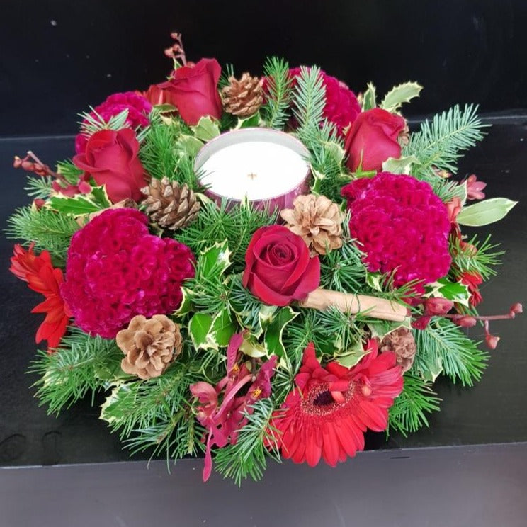 Red & white Christmas floral centrepiece with candle, pine cones and cinnamon sticks