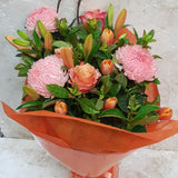 Orange and pink bouquet made with tulips, lilies and roses